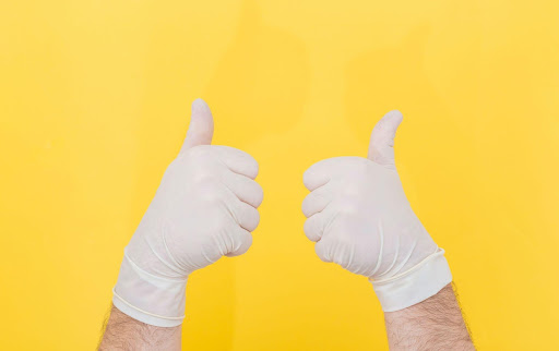 Daumen hoch in medizinischen Handschuhen